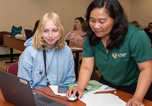 LSSC instructor helps student use laptop in classroom