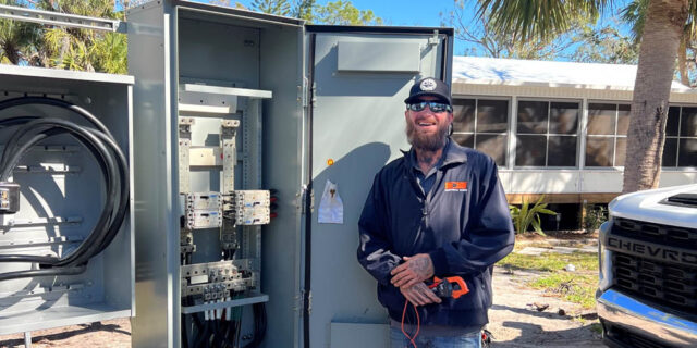 Electrical Apprenticeship student Aaron Fenbers stands in front of an electrical box while on a job site for Electrical Works of Florida