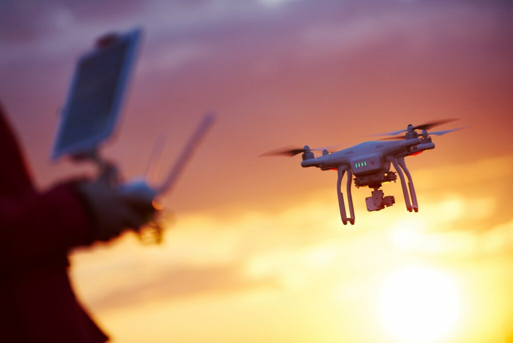 Drone flying at sunset with blurry pilot control in foreground