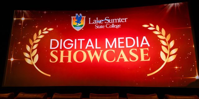 Theater screen showing Lake-Sumter State College Digital Media Showcase, gold laurels, red background; lecture hall setting.