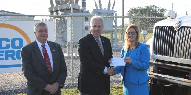Three people posing with check being handed over