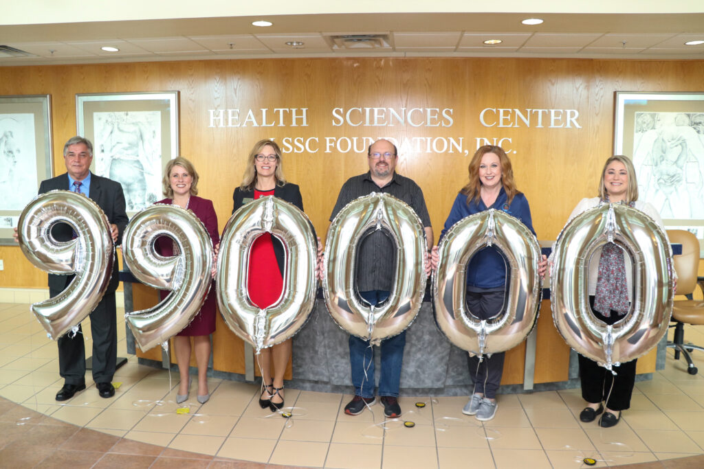 Foundation board members holding large balloons with 990,000