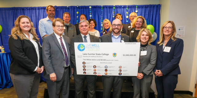 Group of people smiling and standing with a big check for 2 million dollars