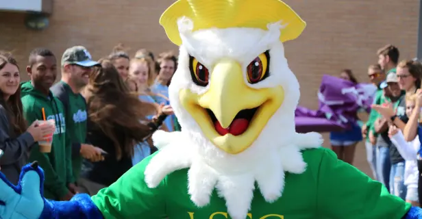 Eagle mascot in yellow hat and green LSSC shirt, surrounded by students.