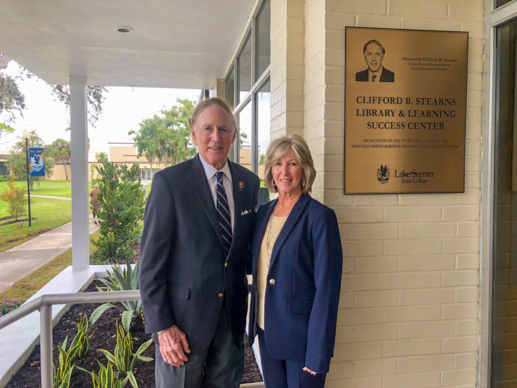 Rep. Stearns and his wife stand next to a gold plaque on the wall