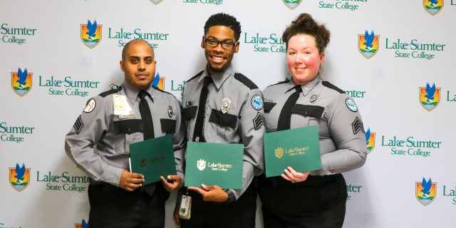 Three corrections officers pose with their completion certificates