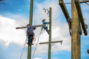 Lineworker worker students work atop utility poles