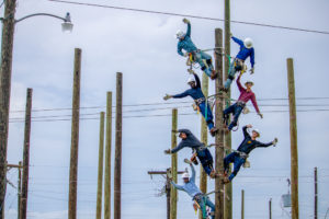 Seven lineworker students on one utility pole celebrating their completion of the program