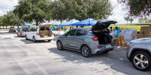 Cars with trunks open line up for food distribution