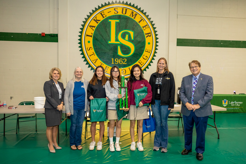 students and faculty standing in line for a photo holding a trophy