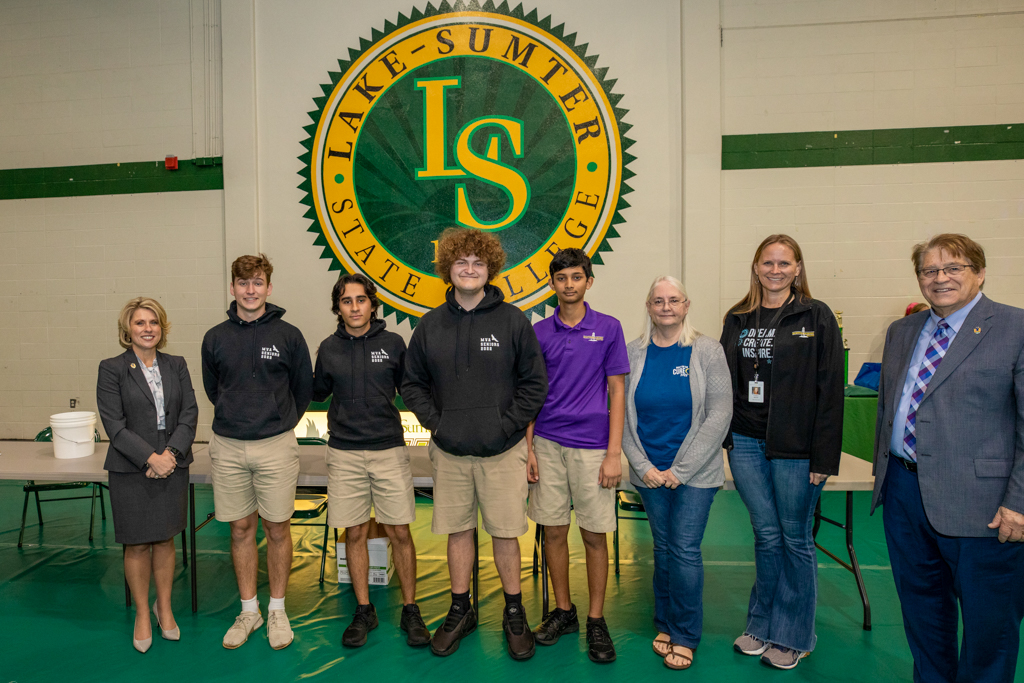 students and faculty standing in line for a photo holding a trophy