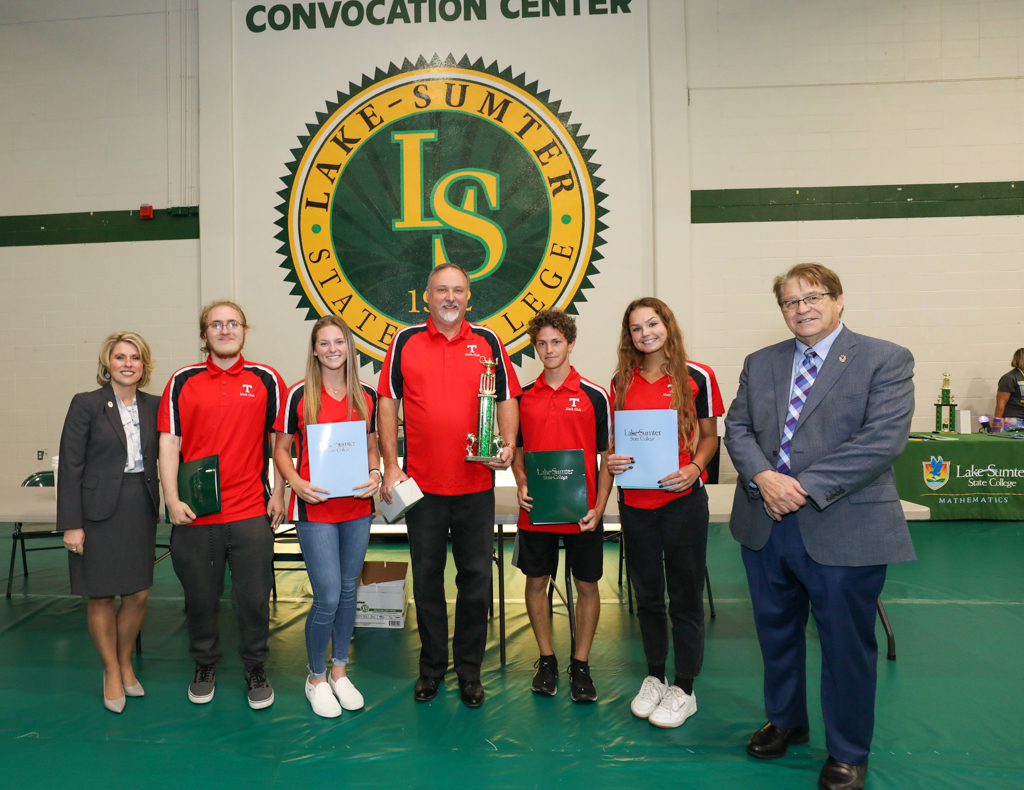 students and faculty standing in line for a photo holding a trophy