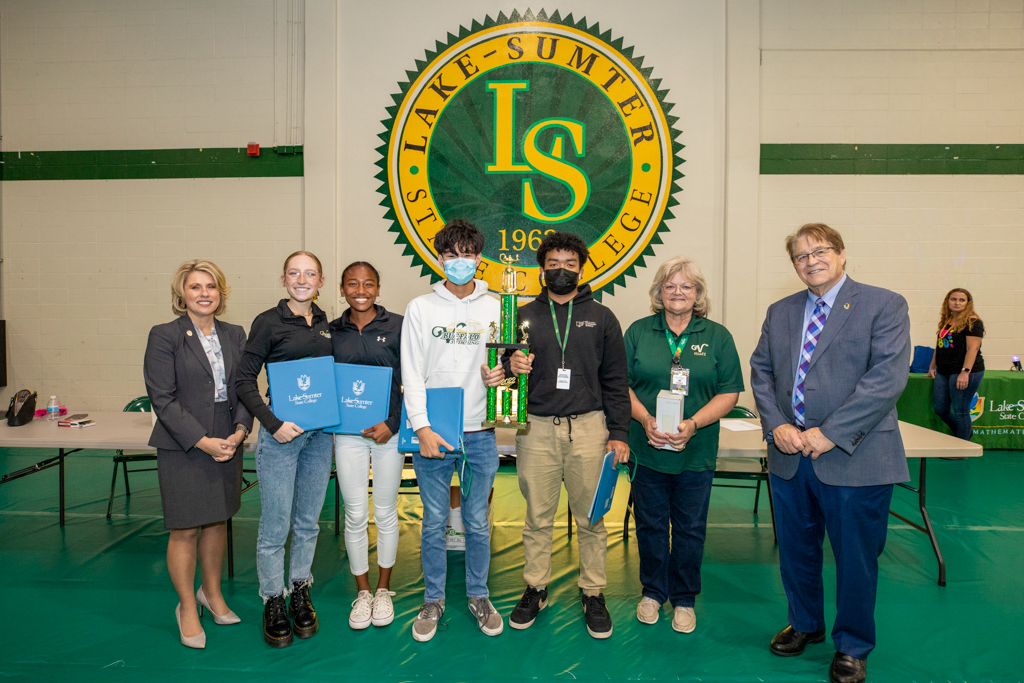 students and faculty standing in line for a photo holding a trophy