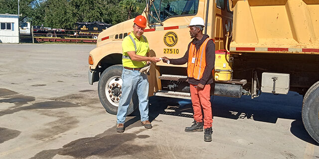 Two men standing in front of a large truck