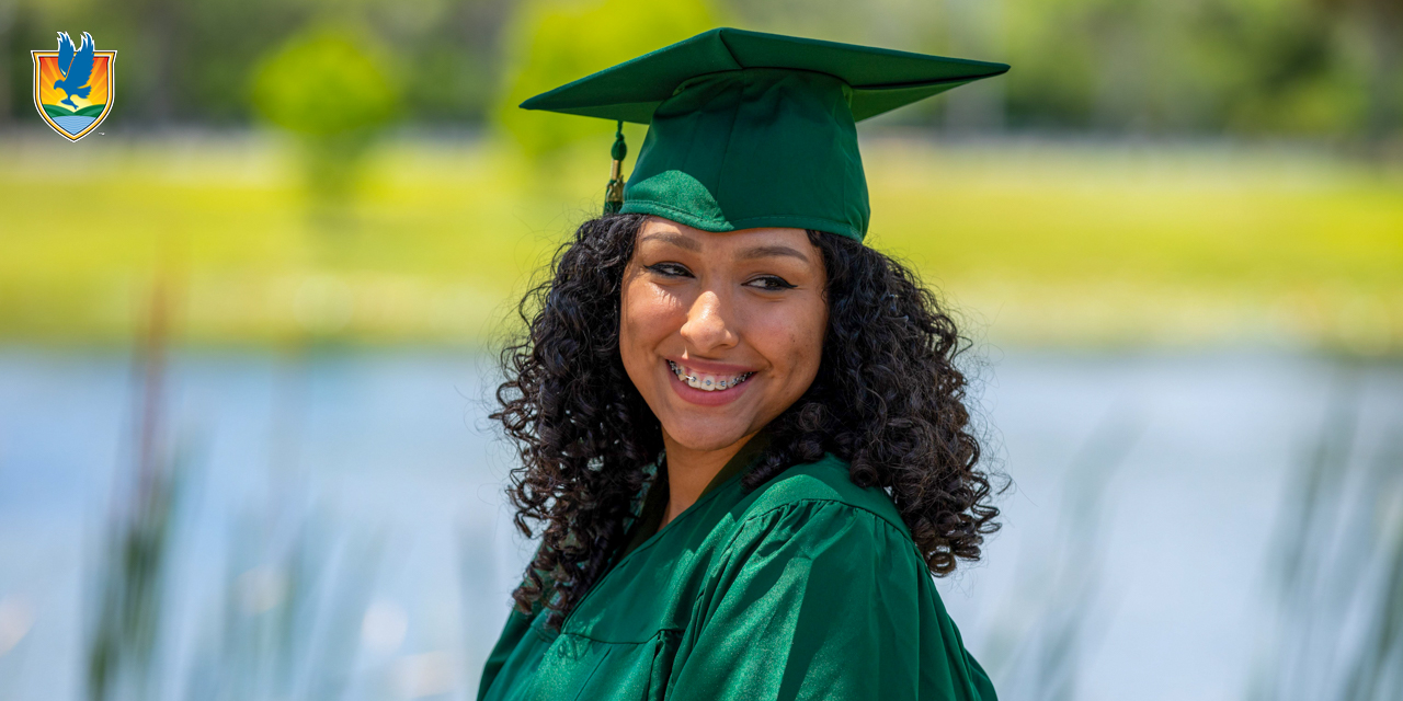 A student smiles while wearing a black graduation cap and gown
