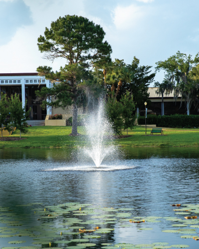 Picture of a pond on campus with a fountain and the Fine Arts Center behind