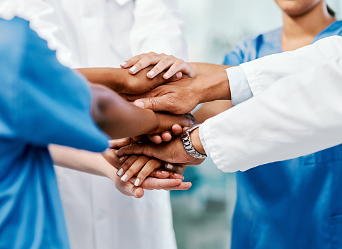 Closeup shot of a group of medical practitioners joining their hands together in a huddle