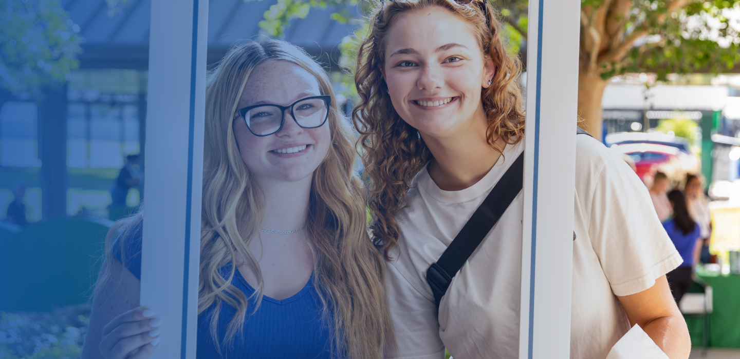 Students posing outdoors, framed by a white window-like structure.
