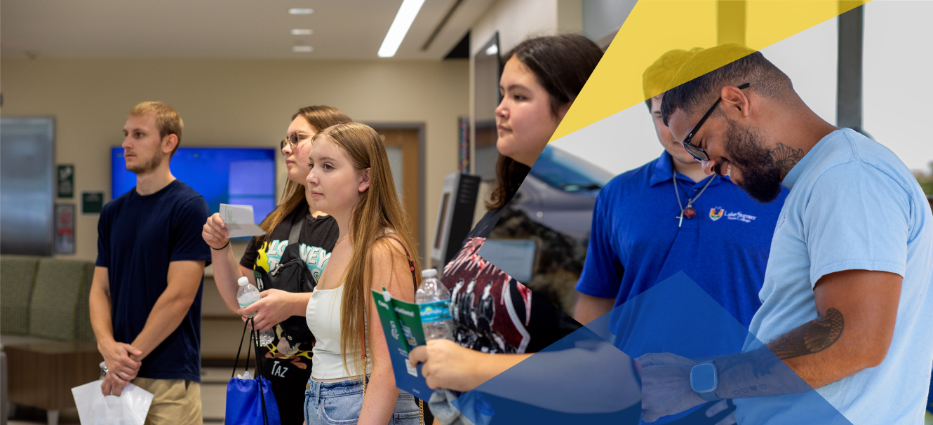 A group of students, some holding papers and booklets, stand indoors in a brightly lit room with modern decor.