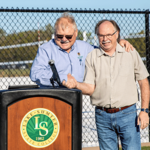 Two people shaking hands at a Lake-Sumter State College podium.
