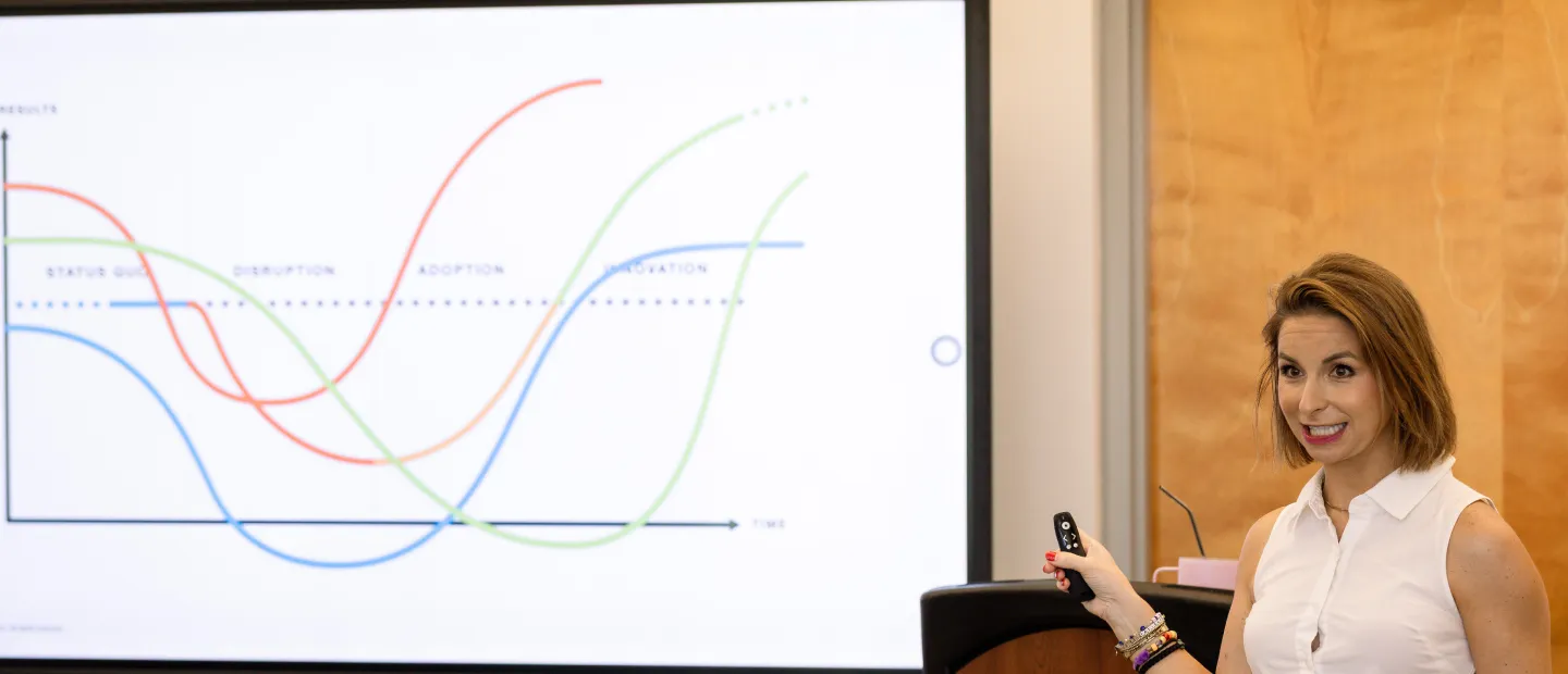 Maria Carey presenting line graph on screen in classroom or meeting room.