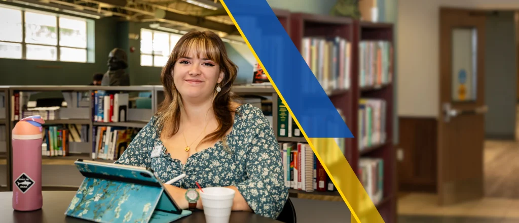 Student smiling with tablet and water bottle in front of her