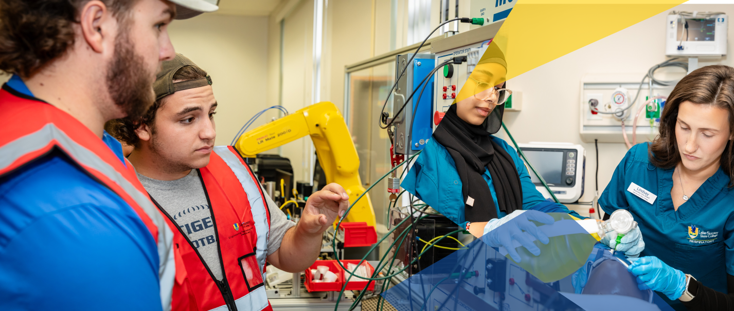Students and instructors in a medical training setting with medical and robotic equipment present.