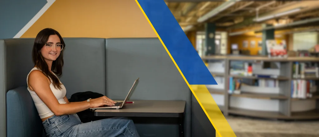 student at library with laptop on desk studying