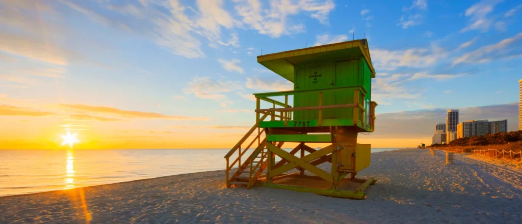 Green lifeguard station on a beach at sunrise.