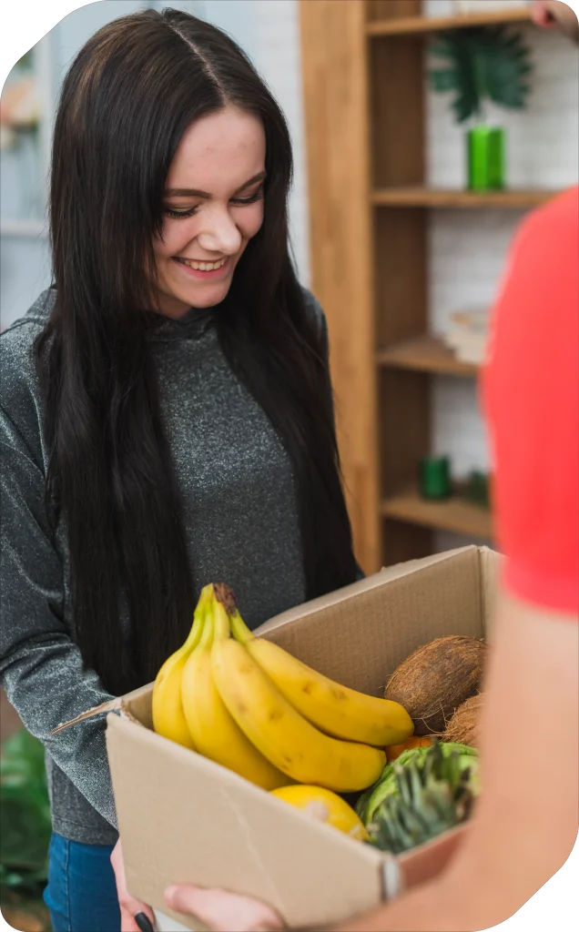 Woman holding a cardboard box filled with fruits and vegetables