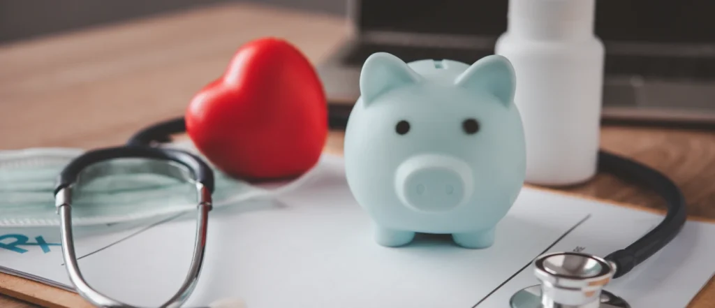 Blue piggy bank, red heart, stethoscope on a table