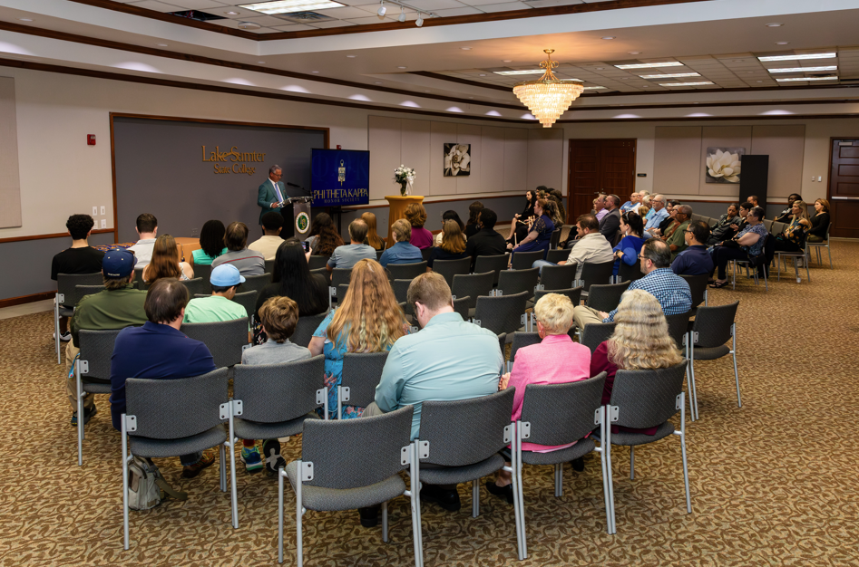 Person speaking to seated audience in conference room, Lake Sumter State College.