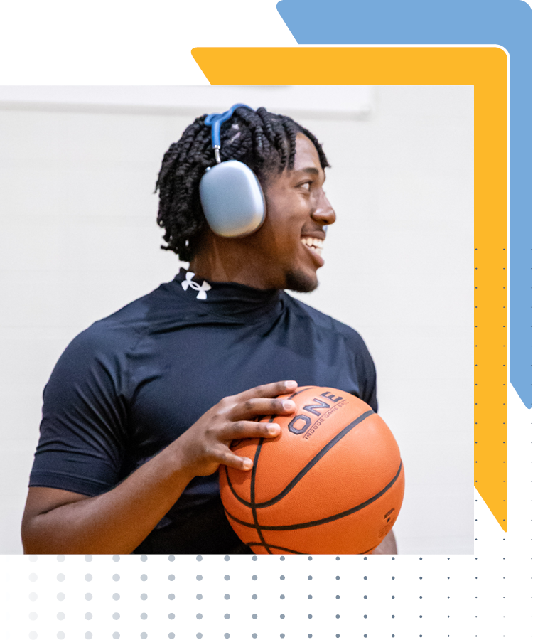 Half portrait of a male student wearing headphones and holding a basketball