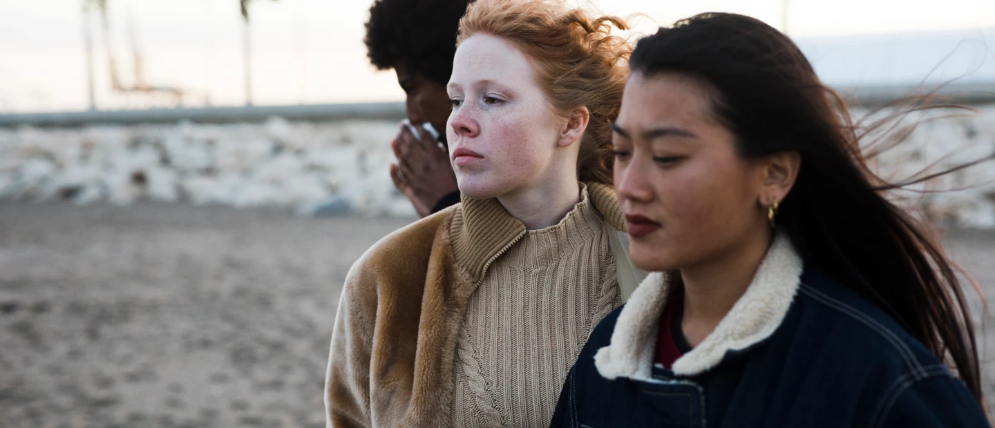 Three people walk along a beach at dusk