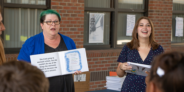 Jackie Pierce and Amber Karlins show the illustrated book to children