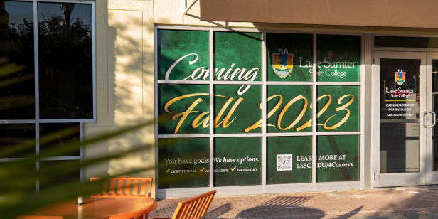 Lake-Sumter State College storefront window display announcing a new location opening Fall 2023.