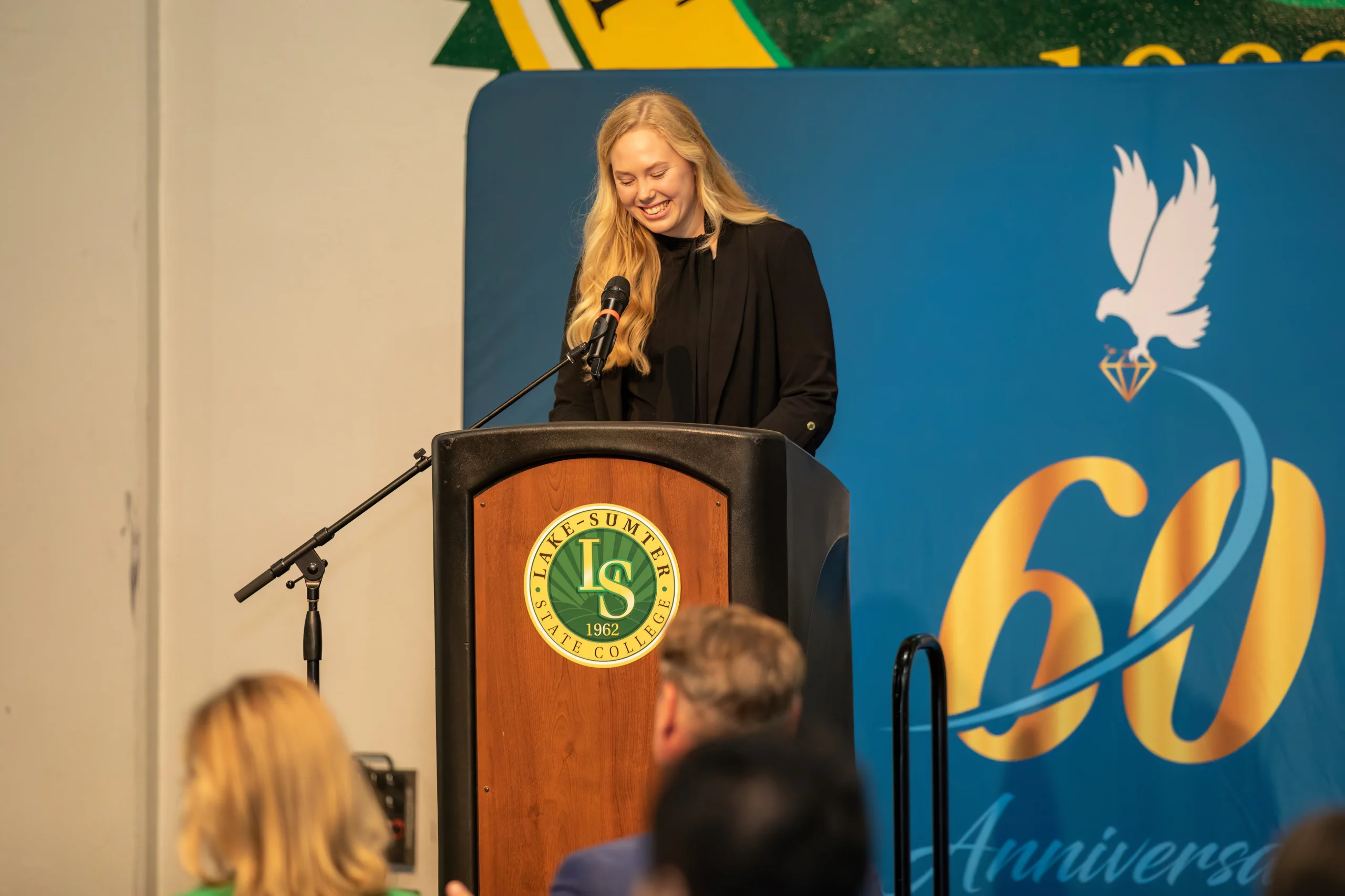 Woman smiling behind a podium at Lake-Sumter State College event.