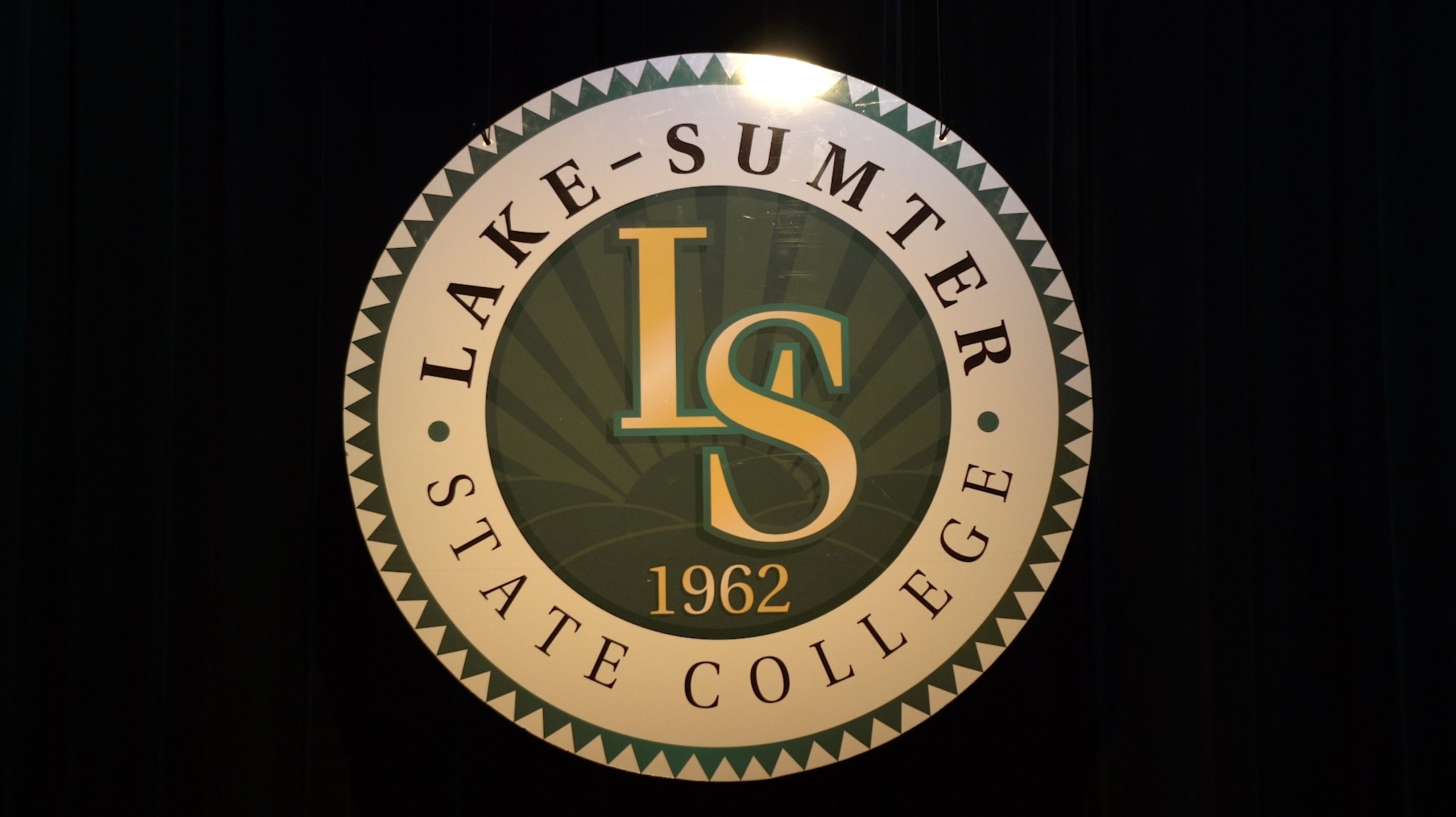 White seal with LS in the middle and Lake-Sumter State College in green text around it