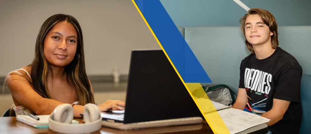 Two students are sitting at a desk with laptops.
