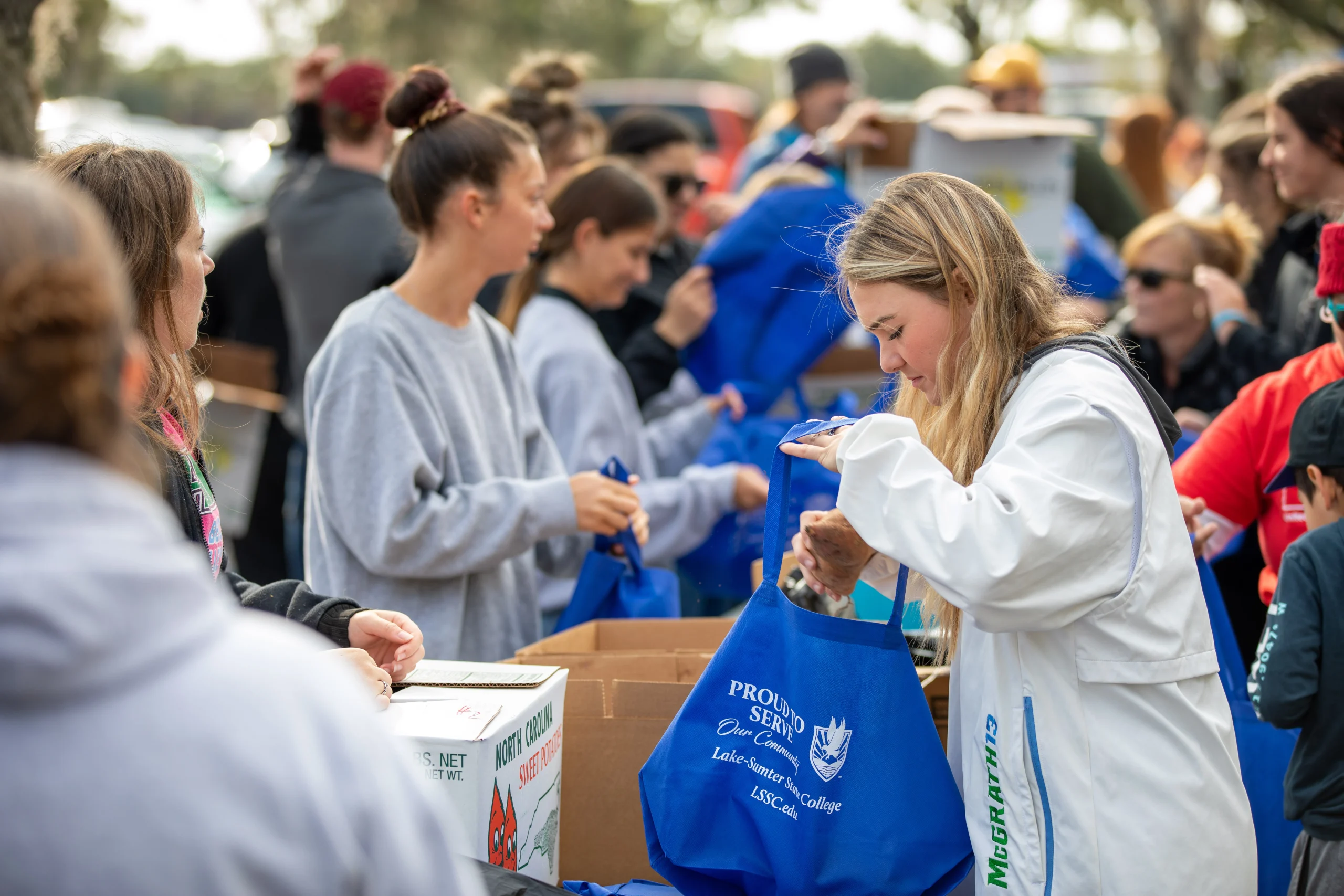 Student hands receive boxes from a volunteer at an event.