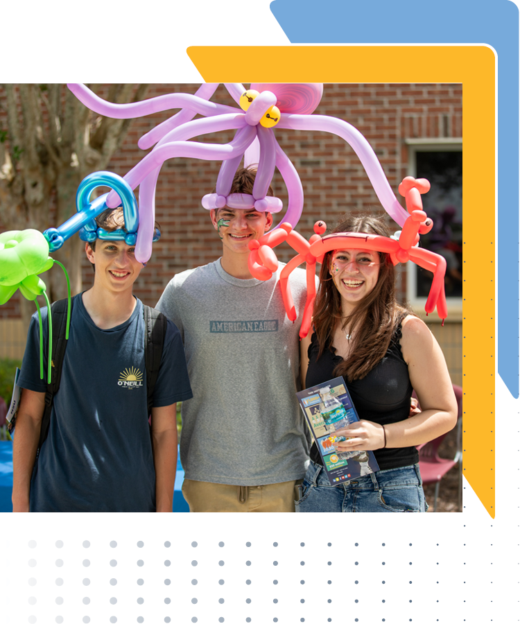 Three college students wearing balloon hats, smiling at the camera during the LSSC Welcome Back Bash